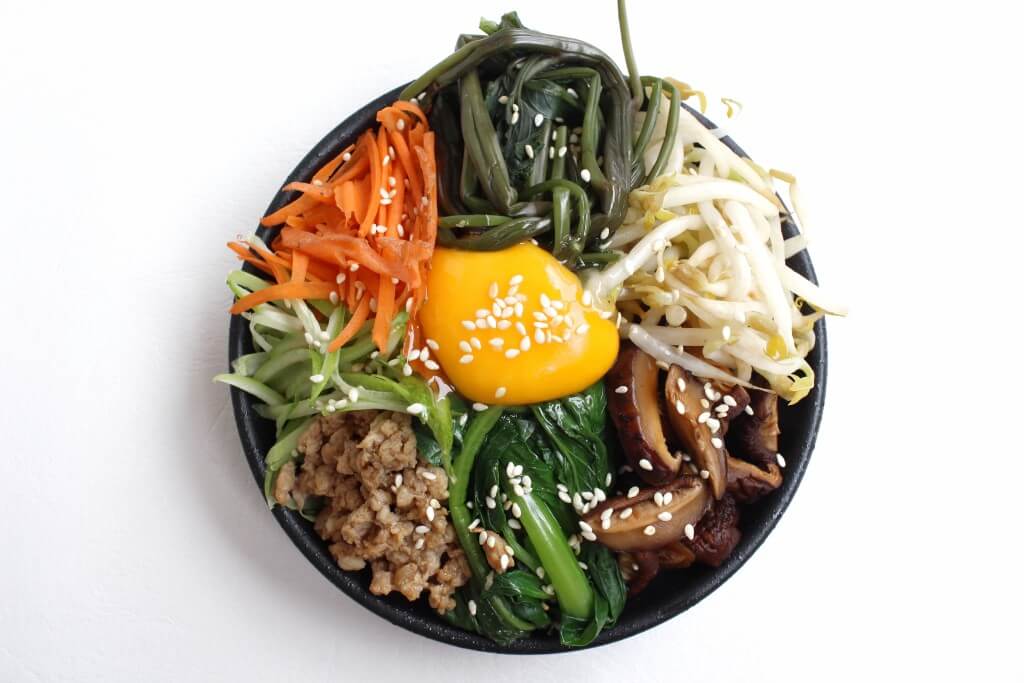 Eine Schale Bibimbap mit Reis, Gemüse, Hackfleisch und Eigelb.