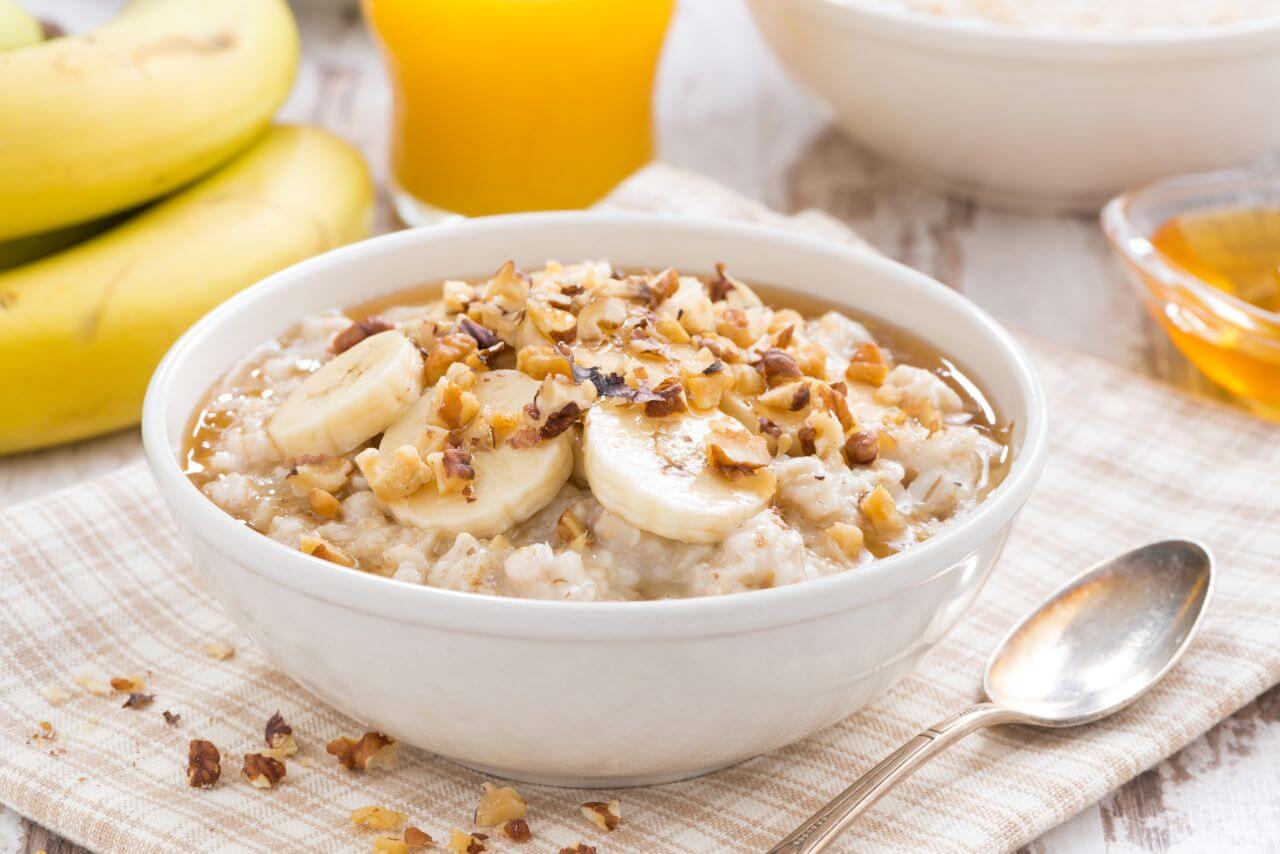 Getreidebrei mit Banane und Honig in einer weißen Schüssel.