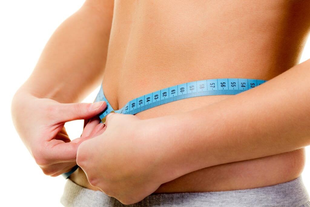 Eine Person misst ihren Bauchumfang mit einem blauen Maßband.