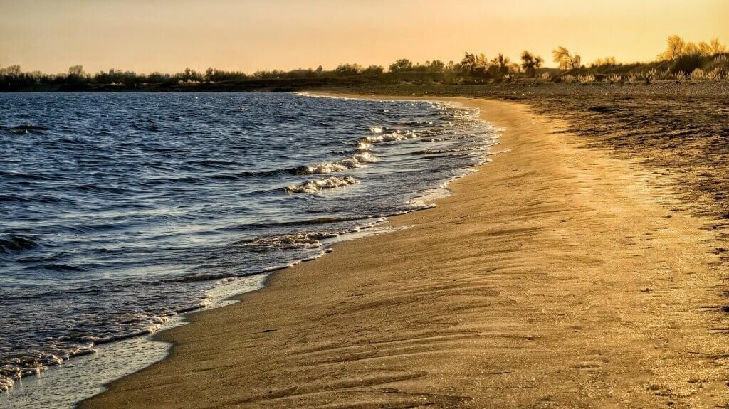 Eine Küstenlandschaft mit einem Sandstrand und Wellen, die ans Ufer rollen.