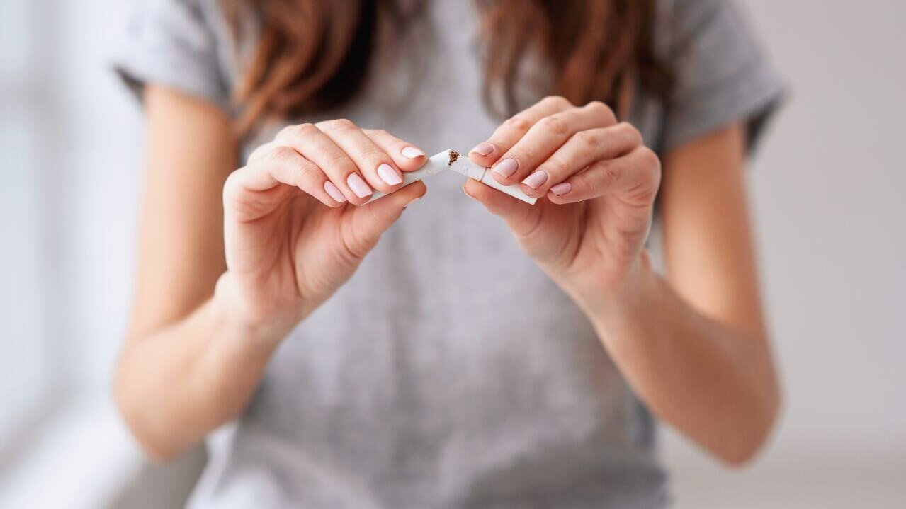 Eine Frau bricht eine Zigarette in der Mitte durch, Fokus auf die Hände.