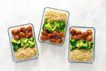 Drei rechteckige Glasbehälter mit geschichtetem Meal Prep.