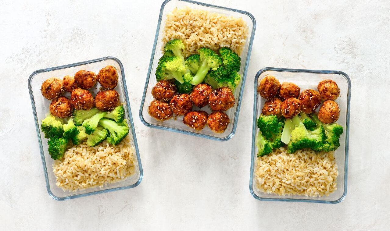 Drei rechteckige Glasbehälter mit geschichtetem Meal Prep.