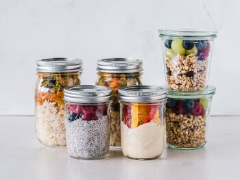 Mehrere Gläser gefüllt mit verschiedenen Schichten von Meal Prep wie Reis, Chia-Pudding und Joghurt mit Früchten.