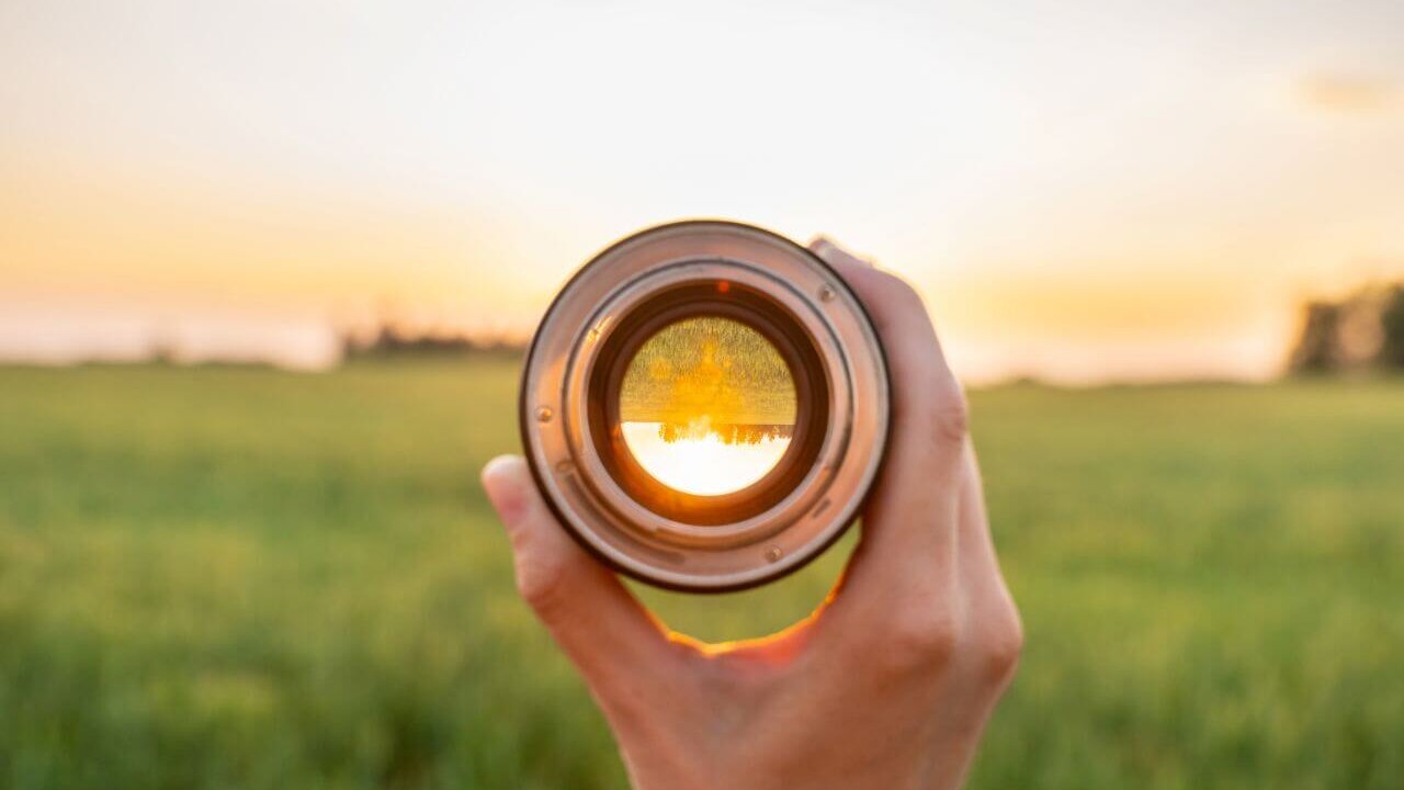 Grüne Wiese und Sonnenuntergang durch eine Kameralinse.