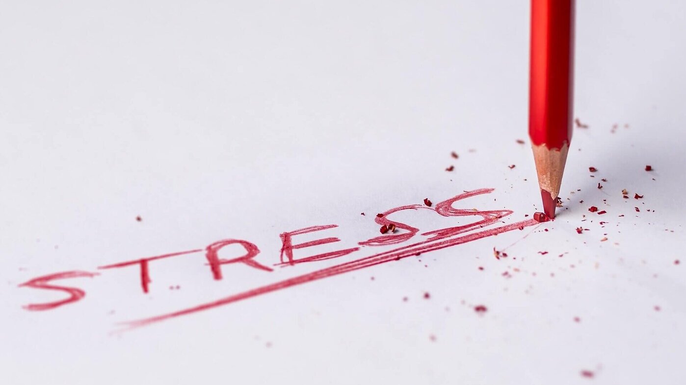 Das Wort "STRESS" ist mit einem roten Stift auf weißes Papier geschrieben.